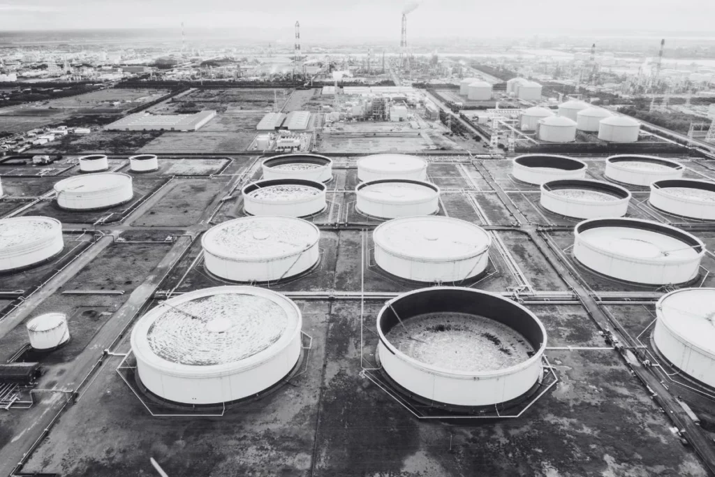 Black and white aerial image of a terminal of floating roof storage tanks. the one in the bottom right corner may have a mechanical shoe seal.